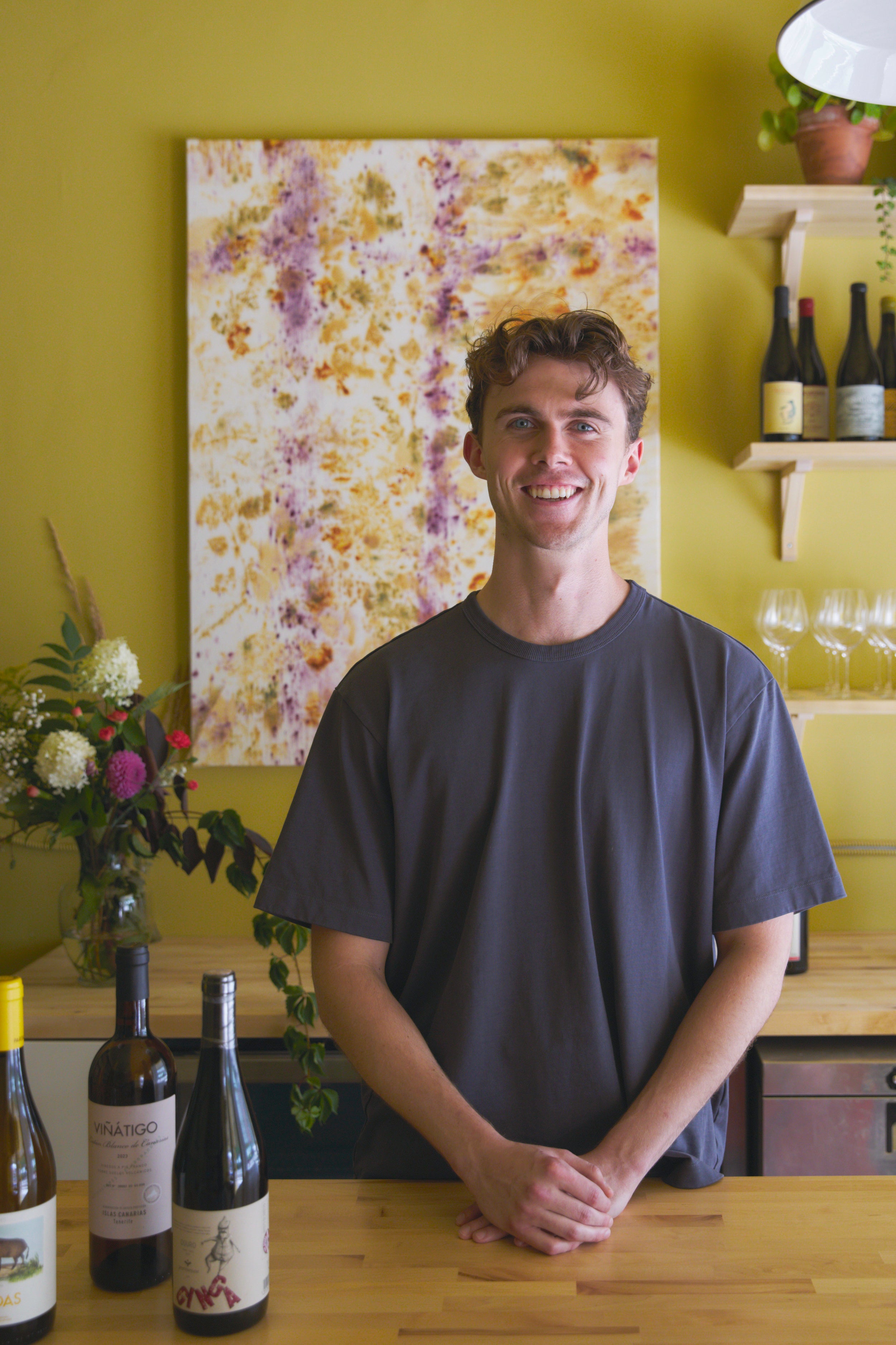 Nate standing at Canary counter with wine bottles.